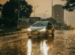 Car with headlights on driving through heavy rain on a wet city street