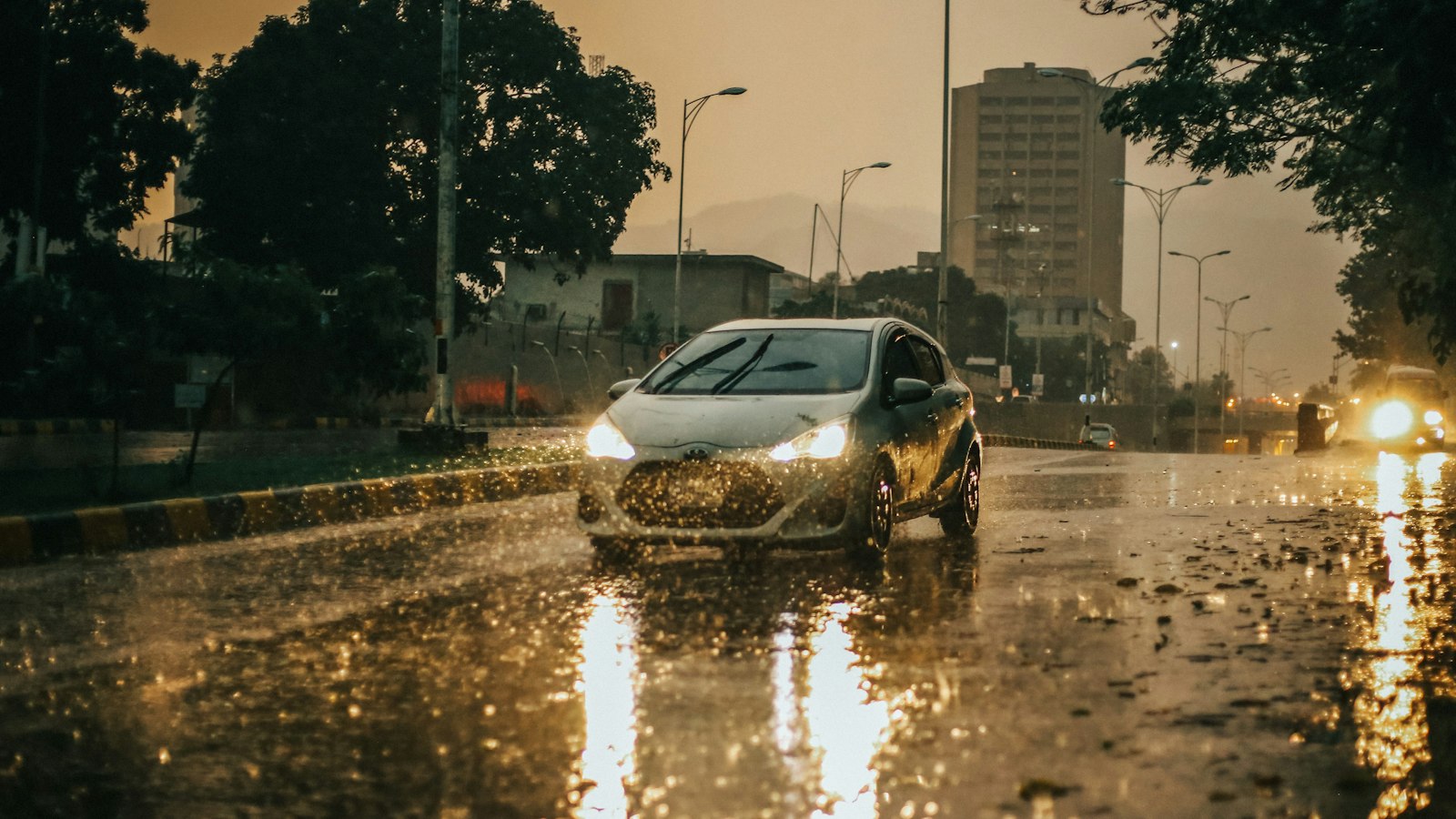 Car driving in the rain on a wet road Car with headlights on driving through heavy rain on a wet city street